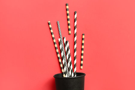 Black paper cup with different drinking straws on red backgroundの写真素材