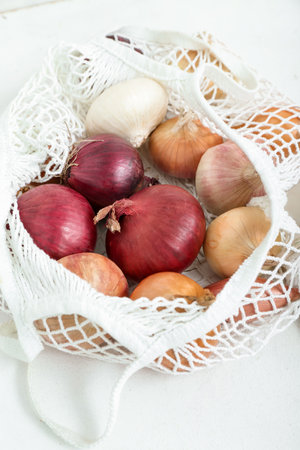 String bag with different kinds of onion on light background, closeupの写真素材