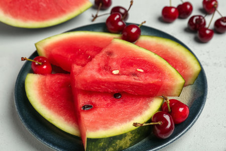 Plate with pieces of fresh watermelon and cherries on gray backgroundの写真素材