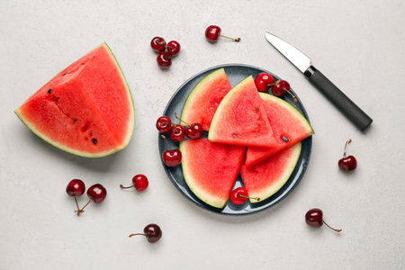 Plate with pieces of fresh watermelon and cherries on gray backgroundの写真素材
