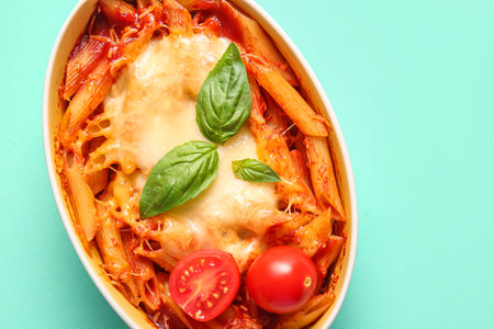 Baking dish of pasta with tomato sauce and cheese on blue background