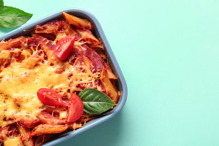Baking dish of pasta with tomato sauce and cheese on blue backgroundの写真素材