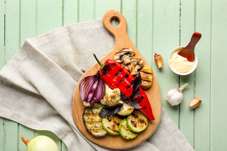 Board with grilled vegetables and sour cream on green wooden backgroundの写真素材