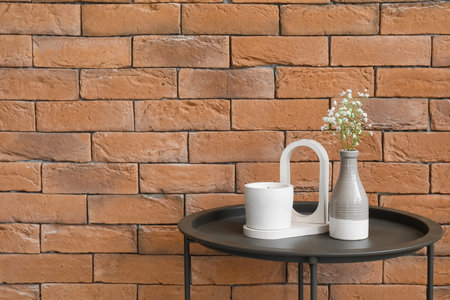 Gypsophila flowers and candle on table near brick wall in roomの写真素材