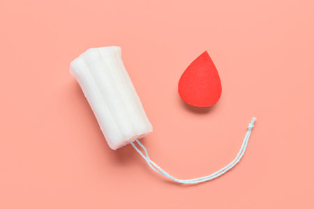 Composition with menstrual tampon and blood drop made of paper on coral backgroundの写真素材