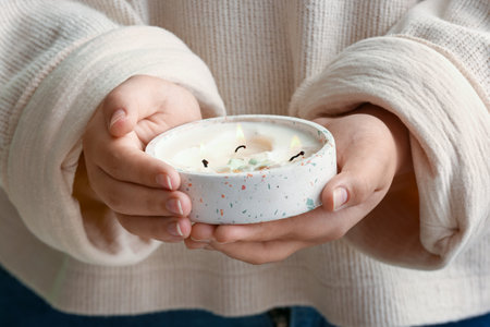 Young woman holding burning candle with flowers, closeupの写真素材