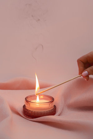 Hand of woman with match lighting candleの写真素材