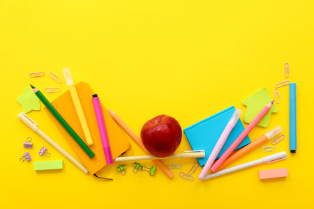 Fresh red apple with different stationery on yellow backgroundの写真素材
