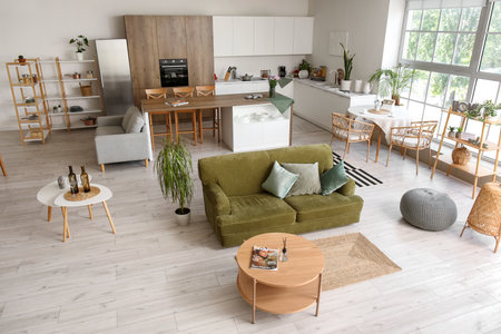Interior of light open plan kitchen with green sofa and coffee tableの写真素材