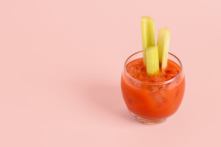 Glass of bloody mary with celery on pink backgroundの写真素材