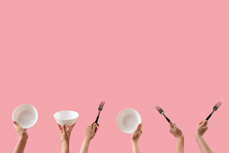 Female hands holding bowls and forks on pink backgroundの写真素材