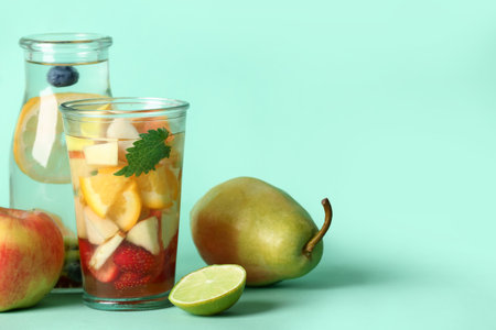 Glass and bottle of infused water with different sliced fruits on blue backgroundの写真素材