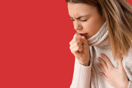 Ill young woman coughing on red background, closeupの写真素材