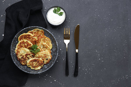 Bowl with tasty zucchini fritters and sour cream on grunge backgroundの写真素材