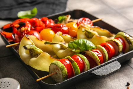Baking dish with tasty grilled vegetables on gray tile backgroundの写真素材