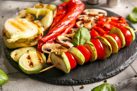 Board with tasty grilled vegetables on gray tile backgroundの写真素材