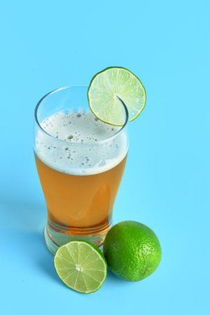 Glass of cold beer with lime on blue backgroundの写真素材