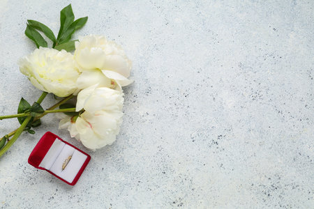 Box with beautiful female ring and peony flowers on light backgroundの写真素材
