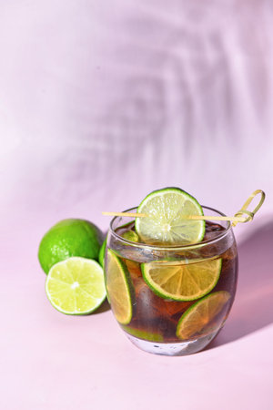 Glass of cold Cuba Libre cocktail on lilac backgroundの写真素材