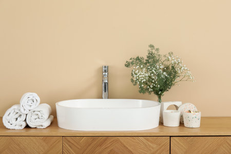 White sink, gypsophila flowers, candles and towels on chest of drawers in bathroomの写真素材