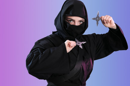 Female ninja with shurikens on color backgroundの写真素材