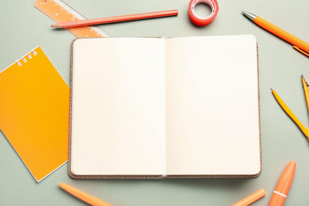 Open notebook with different stationery on gray background