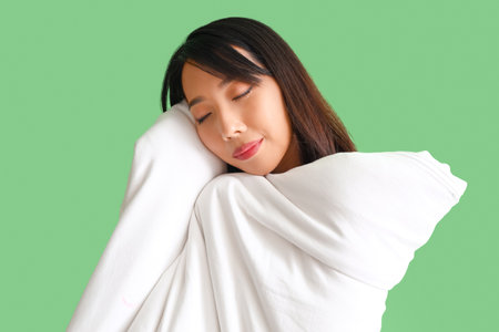 Beautiful Asian woman with blanket on green background, closeupの写真素材
