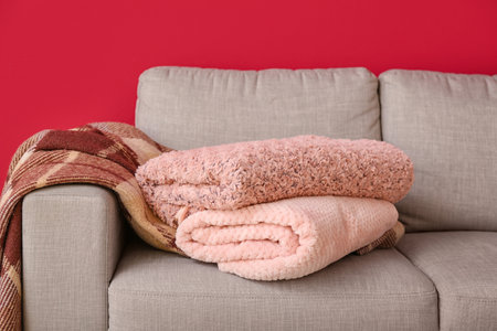 New soft blankets on sofa on burgundy background, closeupの写真素材