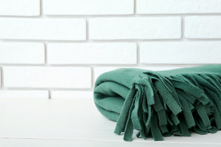 New soft folded blanket on table near light brick wall, closeupの写真素材