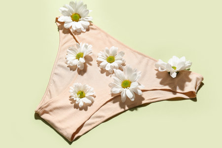 Composition with female panties and beautiful chamomile flowers on green backgroundの写真素材