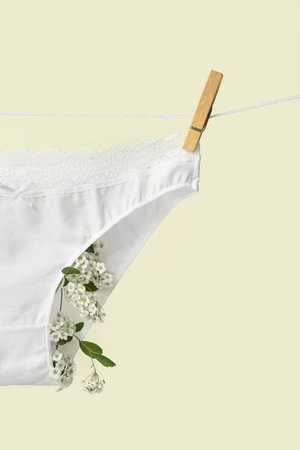 Female panties with blooming plant branches hanging on rope against light background, closeupの写真素材