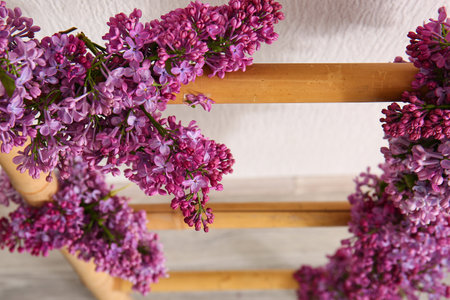 Wooden ladder decorated with beautiful lilac flowers near light wall, closeupの写真素材
