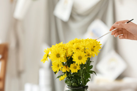 Bouquet of yellow flowers and female artist with brush in studioの写真素材
