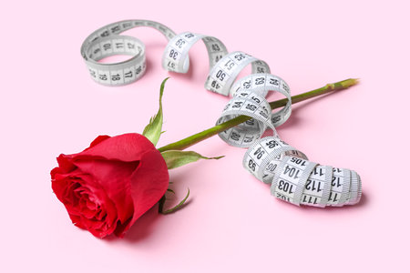 Beautiful rose flower with measuring tape on pink backgroundの写真素材