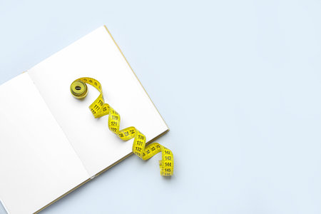 Blank open notebook and measuring tape on light backgroundの写真素材