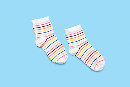 Pair of striped socks on color background
