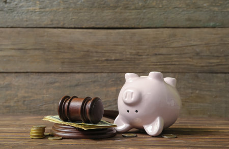Piggy bank with judge gavel and money on brown wooden background. concept of bankruptcyの写真素材