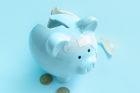 Broken patched piggy bank with money on blue background. bankruptcy conceptの写真素材