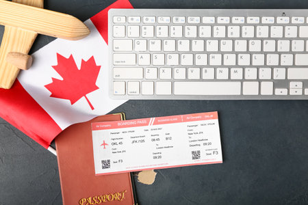 Canadian flag with wooden airplane, passport, ticket and computer keyboard on dark backgroundの写真素材