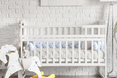 Baby crib with toys in interior of light bedroomの写真素材