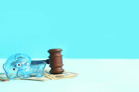 Broken plastic piggy bank with judge gavel and money on blue background. bankruptcy conceptの写真素材
