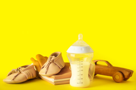 Bottle of milk for baby with accessories on yellow backgroundの写真素材