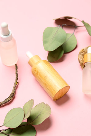 Bottles with cosmetic oil and eucalyptus branch on pink backgroundの写真素材