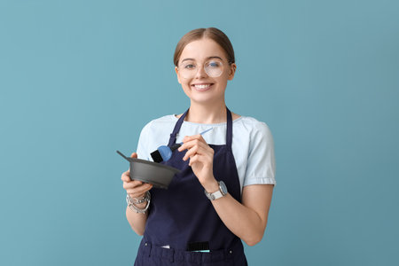 Female hairdresser with bowl and brush for hair dye on blue backgroundの写真素材