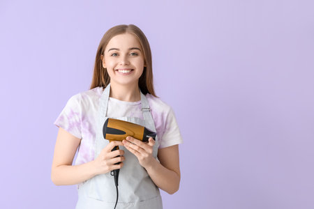 Female hairdresser with dryer on lilac backgroundの写真素材