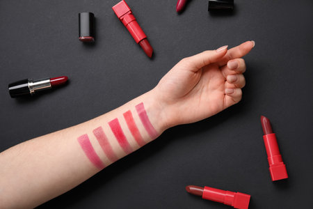 Woman with lipsticks and samples on black backgroundの写真素材