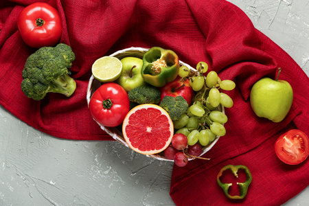 Wicker bowl with different fresh fruits and vegetables on gray backgroundの写真素材