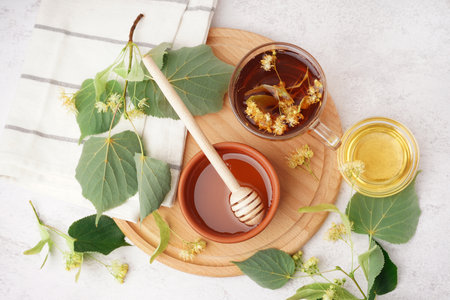Bowl with linden honey and glass cup of tea on white backgroundの写真素材