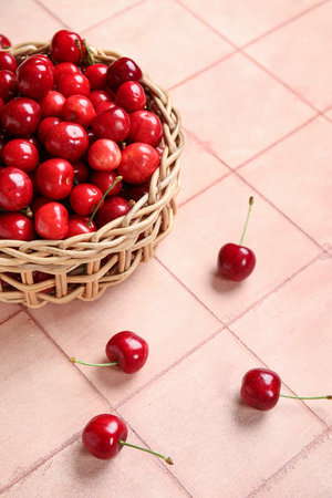 Wicker bowl with sweet cherry on pink tile backgroundの写真素材