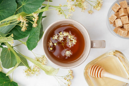 Cup of linden tea and bowl with honey on white tableの写真素材